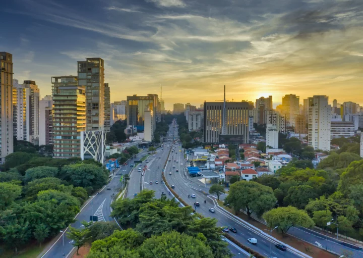 Imagem aérea de carros em pistas cercadas de árvores e prédios durante o anoitecer em São Paulo para ilustrar matéria sobre as cidades com melhor infraestrutura do Brasil