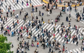 Fotografia de um cidade populosa, com muitas pessoas atravessando na faixa de pedestre.