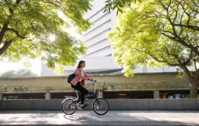 Uma mulher andando de bicicleta em uma cidade sustentável.