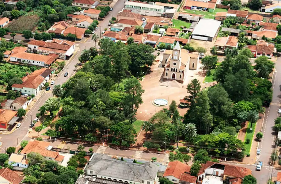  Imagem da vista aérea de Gavião Peixoto, em São Paulo, mostra uma pequena praça da cidade com melhor qualidade de vida do Brasil, com uma igreja no centro, cercada por árvores, uma fonte circular e prédios com telhados vermelhos em todas as ruas
