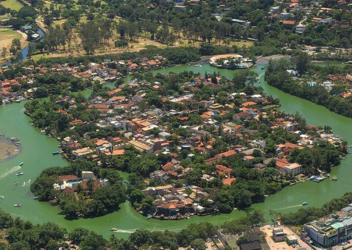 Imagem da vista aérea da Ilha da Gigóia, no Rio de Janeiro, mostra água, vegetação e casas na ilha