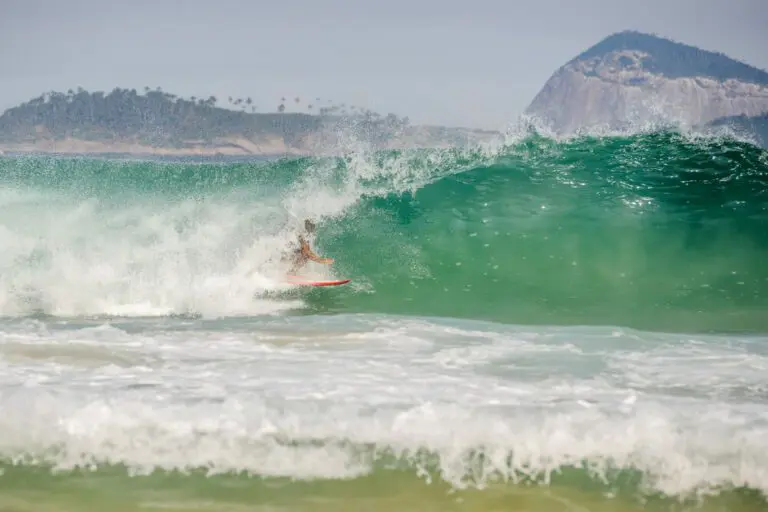 Imagem de surfista pegando onda no mar com as Ilhas Cagarras, no Rio de Janeiro, ao fundo