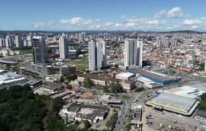 Imagem da vista área de Mogi das Cruzes mostra arranha-céus altos, edifícios de médio porte, áreas residenciais e comerciais, estradas, vegetação e um céu azul claro para ilustrar matéria sobre o que fazer em Mogi das Cruzes.