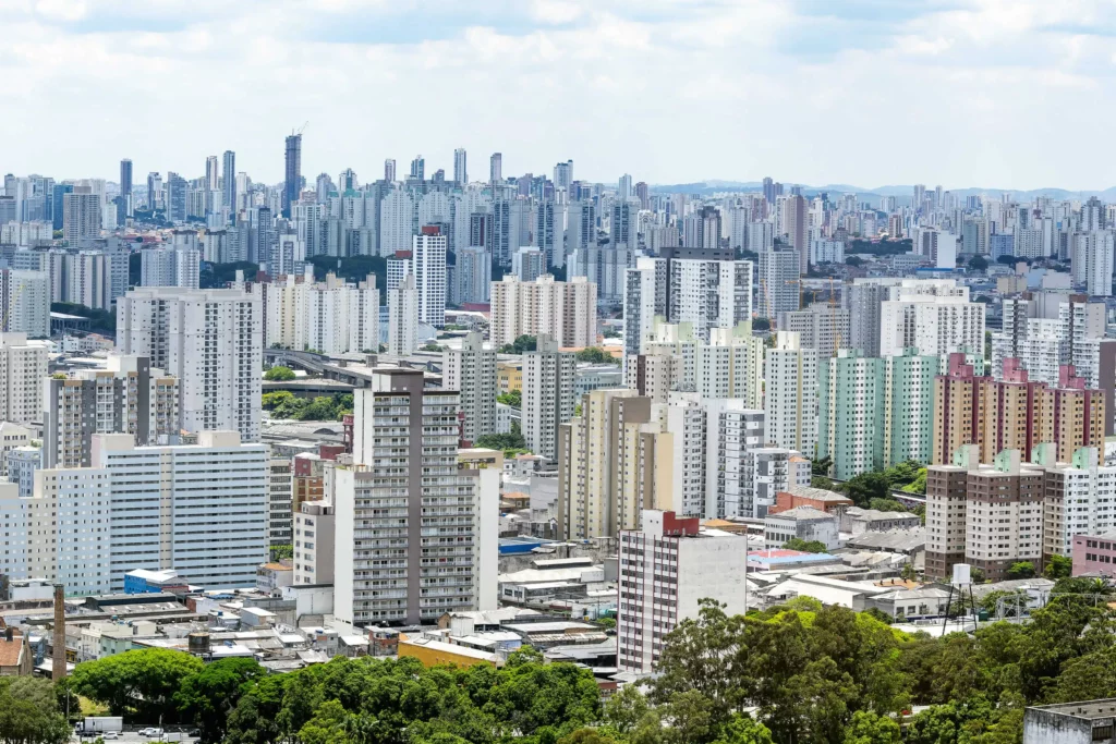 Imagem da vista aérea do bairro Brás, na Zona Leste de São Paulo, mostra vegetação e edifícios ao fundo em um dia de céu azul
