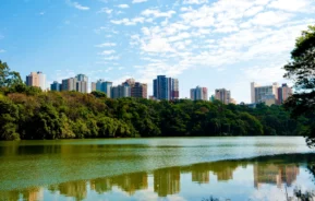 Foto de um parque de Maringá com prédios ao fundo.