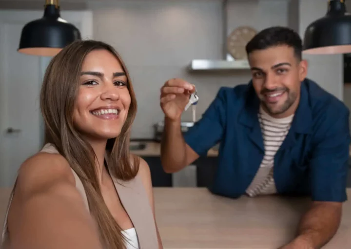 Imagem de um homem e uma mulher posando para uma foto dentro da cozinha de uma casa enquanto o homem segura as chaves de um imóvel para ilustrar matéria sobre fiador