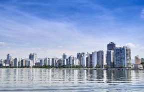 Vista aérea da paisagem urbana de Santos mostra mar e prédios à beira-mar para ilustrar matérias sobre morar em Santos e trabalhar em São Paulo