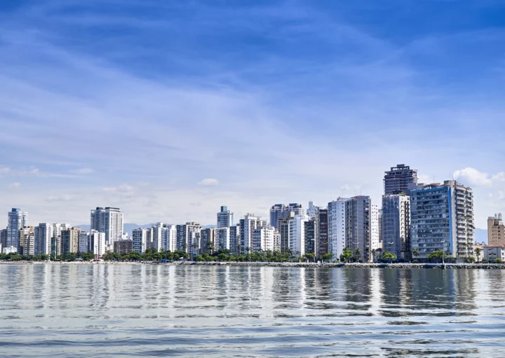 Vista aérea da paisagem urbana de Santos mostra mar e prédios à beira-mar para ilustrar matérias sobre morar em Santos e trabalhar em São Paulo