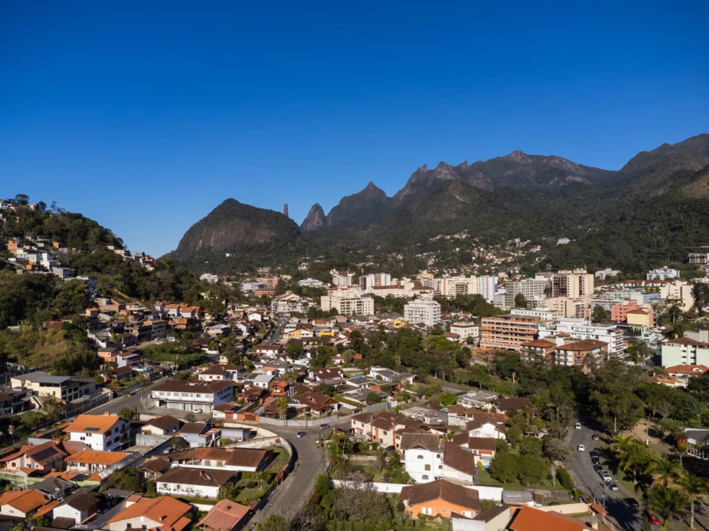 Vista aérea da cidade de Teresópolis mostra casas, prédios, montanhas e um céu azul para ilustrar matéria sobre qual a cidade mais segura do RJ