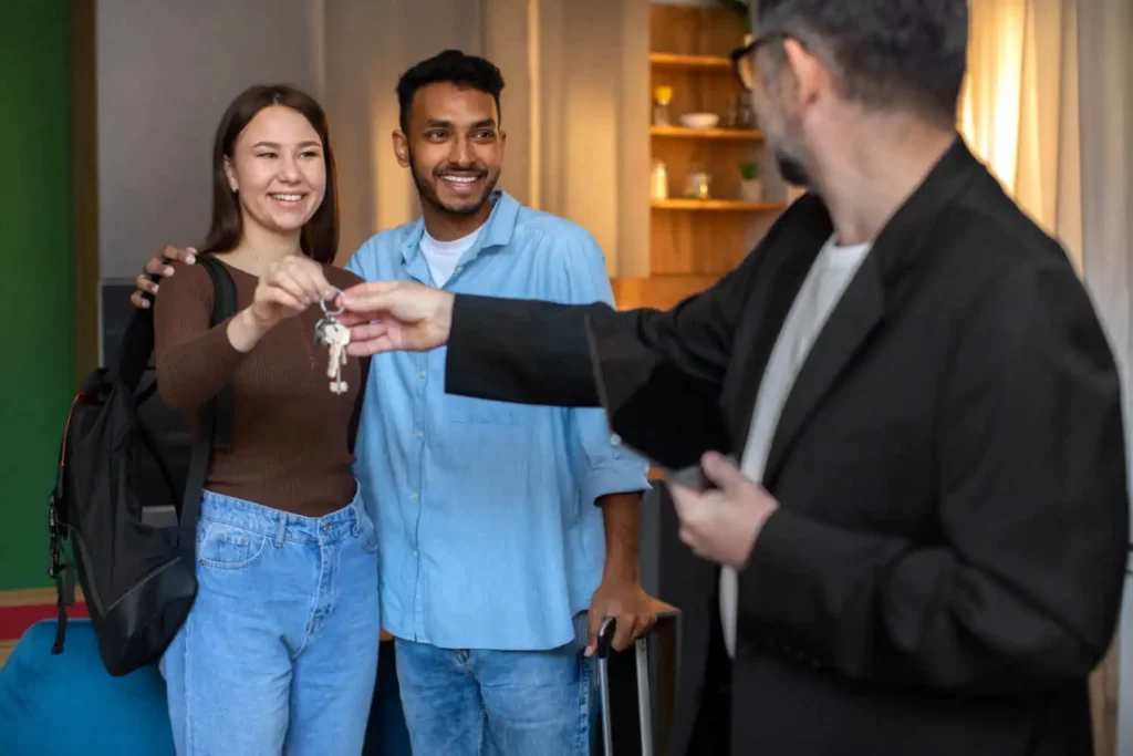 Imagem de um agente imobiliário entregando as chaves de um imóvel a um casal formado por um homem e uma mulher para ilustrar matéria sobre o termo de entrega de chaves ao comprador