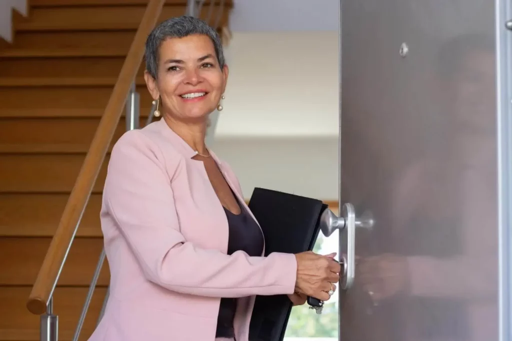 Imagem de uma corretora de imóveis abrindo as portas de uma casa para ilustrar matéria sobre o termo de entrega de chaves ao locatário