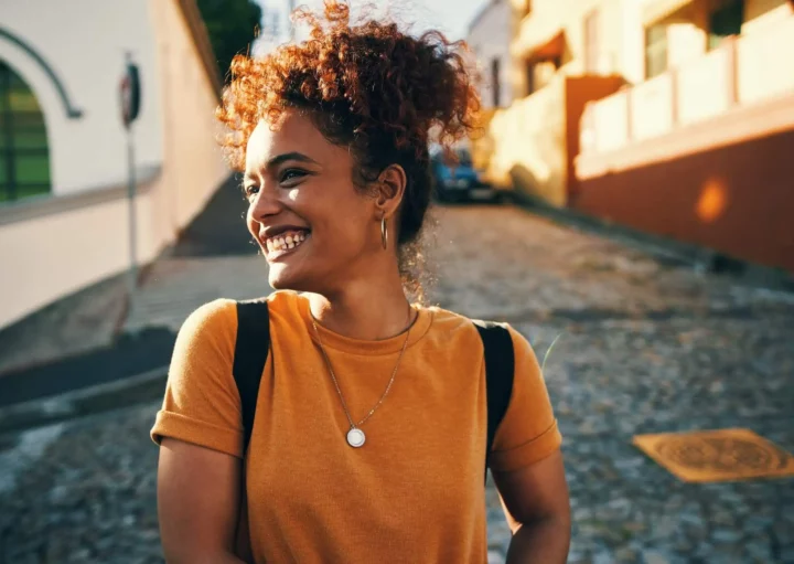 Imagem de uma mulher sorridente andando por uma rua para ilustrar matéria sobre as cidades mais desenvolvidas do Brasil