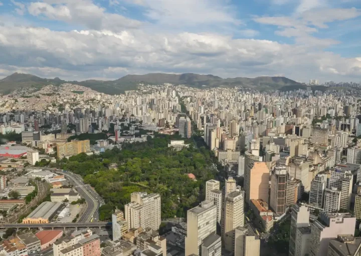 Foto que ilusta matéria sobre cidade mais populosa de Minas Gerais mostra Belo Horizonte vista do alto, com destaque para o Parque Municipal Américo Renne Giannetti em meio a prédios do Centro em primeiro plano e a Serra do Curral ao fundo (Foto: Pedro Vilela | Mtur)