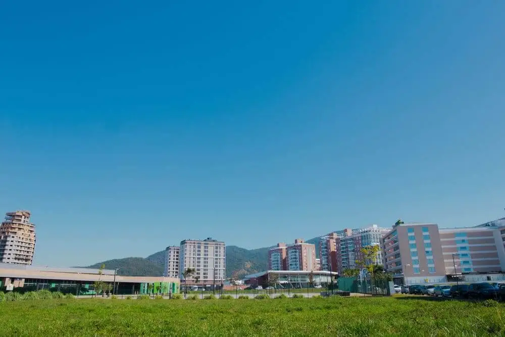 Imagem de área urbana de Palhoça mostra prédios e gramado em um dia de céu azul para ilustrar matéria sobre as cidades de Santa Catarina com praia