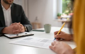 Foto de duas pessoas assinando um contrato.