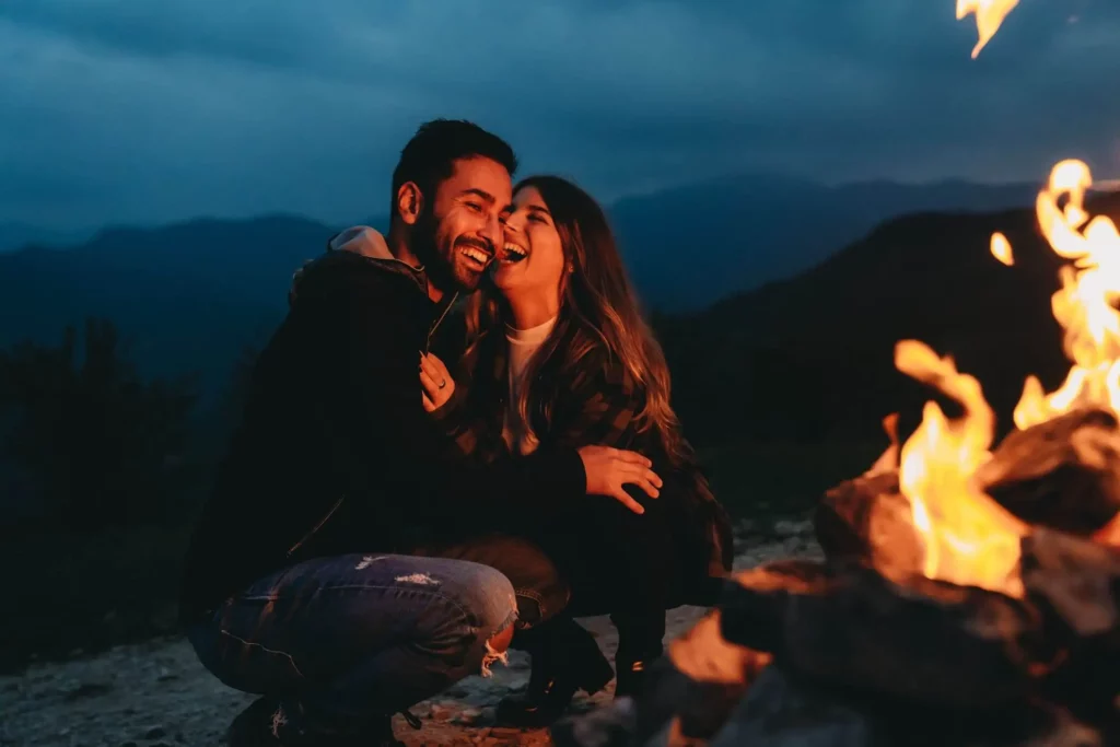 Imagem de um casal se abraçando e sorrindo próximo a uma lareira para ilustrar matéria sobre frio em Itapeva, município do estado de São Paulo