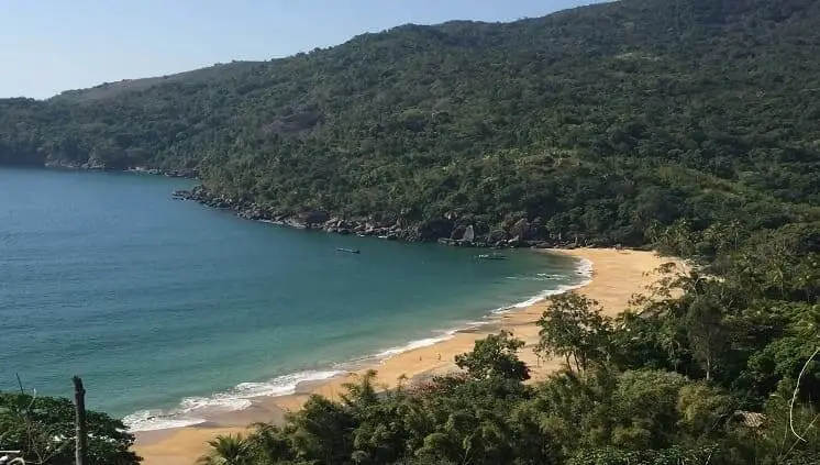 Imagem da vista aérea da Praia de Jabaquara, em Ilhabela, mostra mar, faixa de areia e vegetação em dia ensolarado