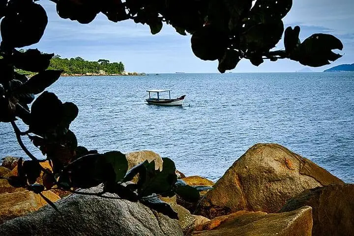 Imagem de um barco navegando no mar da Praia do Julião, em Ilhabela, para ilustrar matéria sobre as melhores praias de SP para casal