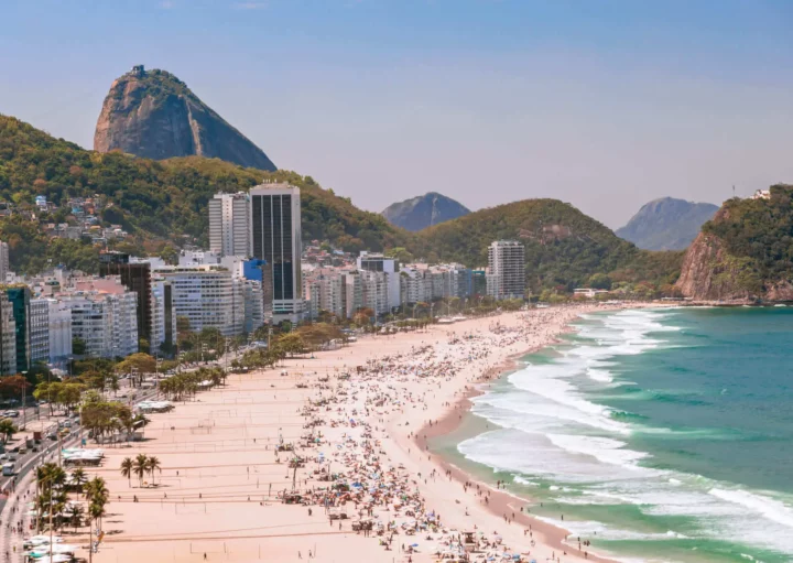 Imagem da praia de Copacabana mostra mar, faixa de areia, prédios e vegetação para ilustrar matéria sobre o que fazer na zona sul do Rio de Janeiro