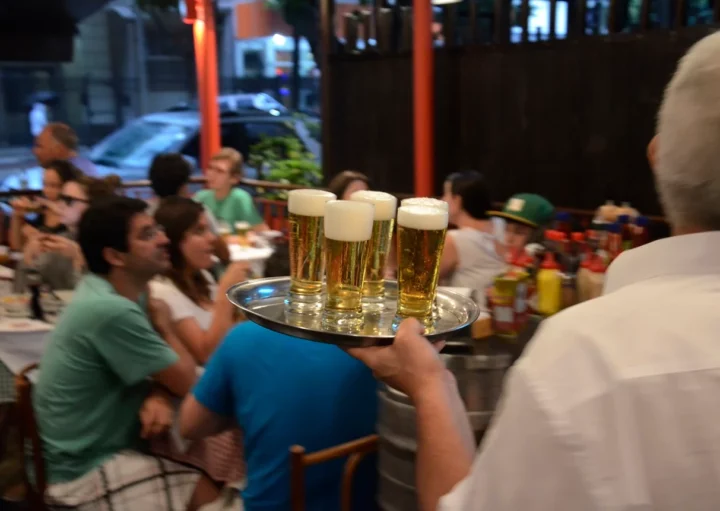 Foto que ilustra matéria sobre melhor vida noturna no Brasil mostra um garçom de costas com uma bandeja com copos cheios de chope nas mãos (Foto: Alexandre Macieira | Riotur)