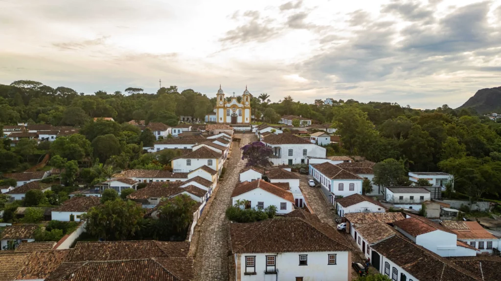 Imagem aérea de cidade histórica Tiradentes, em Minas Gerais, com capela amarela no alto do morro, para ilustrar matéria sobre quais são as cidades que mais crescem em Minas Gerais