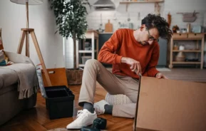 Imagem de um homem abrindo uma caixa de papelão durante uma mudança para ilustrar matéria sobre ação de despejo no juizado especial