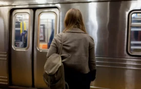 Imagem de uma mulher de costas com uma mochila pendurada nos ombros em frente a um trem em uma estação de metro para ilustrar matéria sobre a Linha 15-Prata