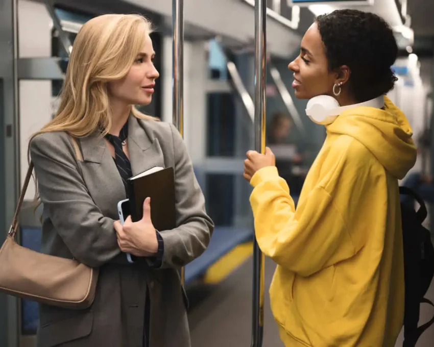 Imagem de duas mulheres paradas em pé uma em frente da outra dentro de um trem do metrô para ilustrar matéria sobre a Linha 5-Lilás, de São Paulo