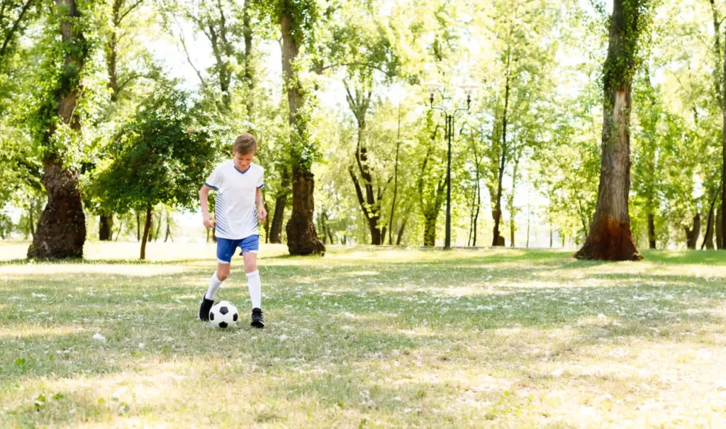 Imagem de uma criança chutando uma bola em meio a um parque para ilustrar matéria sobre o Parque do Carmo, que fica localizado na Zona Leste da capital paulista