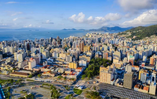 Imagem da vista aérea da capital de Santa Catarina mostra prédios, avenidas e mar ao fundo para ilustrar matéria sobre os bairros mais populosos de Florianópolis