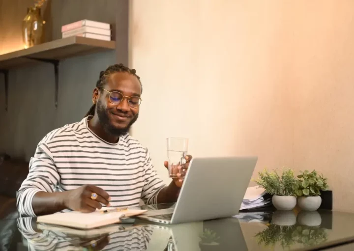 Foto que ilustra matéria sobre apartamento sem condomínio mostra um homem sentado com um laptop aberto a sua frente em uma mesa e um caderno ao lado (Foto: Shutterstock)