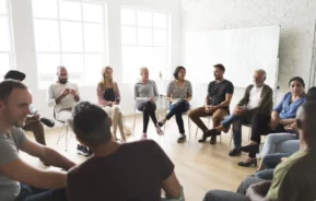 Foto que ilustra matéria sobre convenção de condomínio mostra pessoas sentadas em cadeiras reunidas em um grande círculo (Foto: Shutterstock)