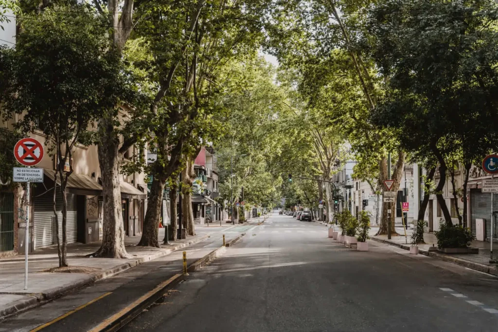 Imagem de um bairro mostra avenida, calçada, prédios, sinalização e árvores para ilustrar matéria sobre como avaliar a infraestrutura de um bairro