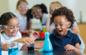 Imagem de duas meninas animadas na escola durante um experimento de química para ilustrar matéria sobre as escolas particulares em Nilópolis