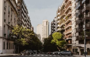 Imagem de um bairro com prédios residenciais, árvores e carros estacionados para ilustrar matéria sobre infraestrutura de um bairro