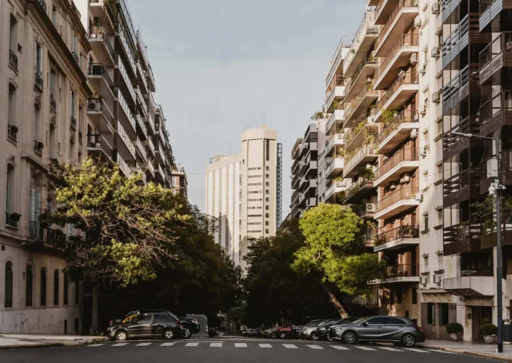 Imagem de um bairro com prédios residenciais, árvores e carros estacionados para ilustrar matéria sobre infraestrutura de um bairro