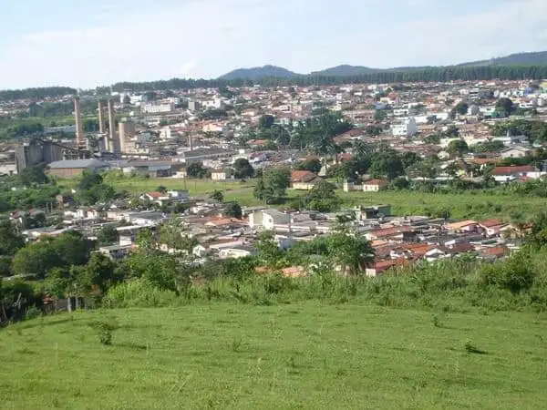 Imagem da vista aérea de Itaú de Minas mostra vegetação, casas e indústria ao fundo