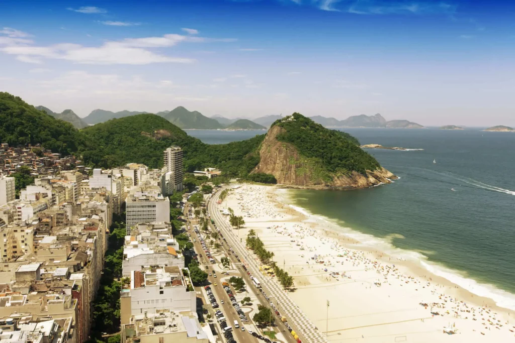 Imagem da vista aérea da Praia do Leme, no Rio de Janeiro, mostra montanhas, mar, faixa de areia, prédios e vegetação para ilustrar matéria sobre as melhores praias da Barra da Tijuca