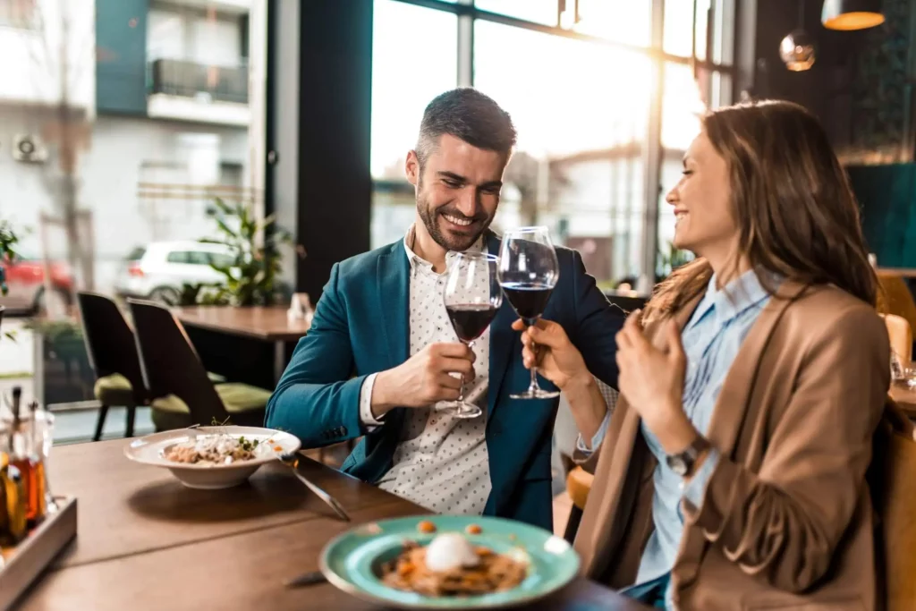 Imagem de um casal brindando com uma taça de vinho sentados na mesa de um restaurante para ilustrar matéria sobre os melhores restaurantes de São Paulo