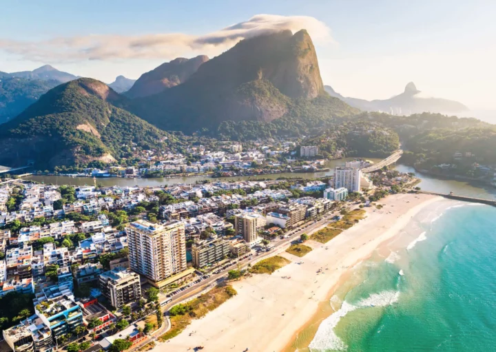 Imagem da vista aérea da paisagem da Barra da Tijuca mostra mar, faixa de areia, prédios e construções na beira da orla, vegetação e montanhas da região para ilustrar matéria sobre as praias da Barra da Tijuca, no Rio de Janeiro