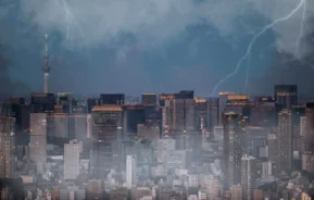 Imagem da vista aérea de uma cidade durante uma tempestade com raios para ilustrar matéria sobre os danos causados por chuva em imóvel alugado