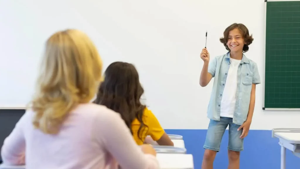 Imagem de um aluno em frente à turma do colégio enquanto outras estudantes sentadas prestam atenção para ilustrar matéria sobre escola em Duque de Caxias
Título: escola em duque de caxias
