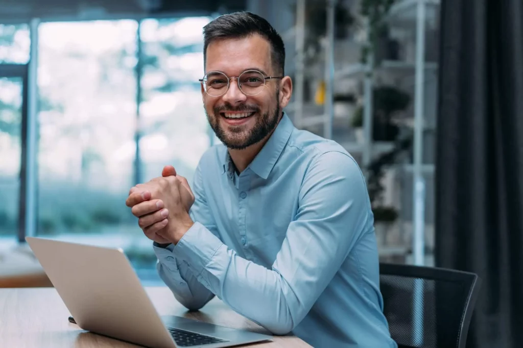 Imagem de um homem com roupa social sentado em um escritório em frente a um notebook para ilustrar matéria sobre os melhores bairros para investir em imóveis em SP