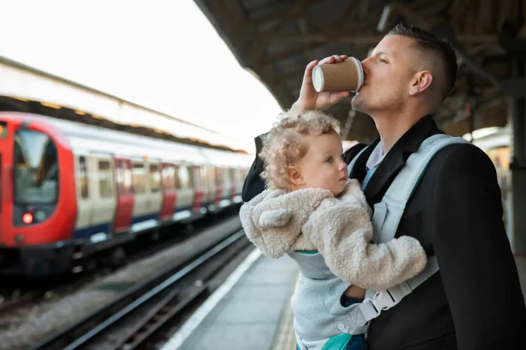 Imagem de um homem tomando um copo de café em uma estação de metrô com uma criança no colo para ilustrar matéria sobre o que fazer em São Paulo