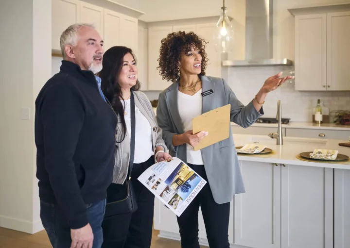 Imagem de um casal formado por um homem e uma mulher visitando um imóvel na companhia de uma corretora imobiliária para ilustrar matéria sobre captação de imóveis