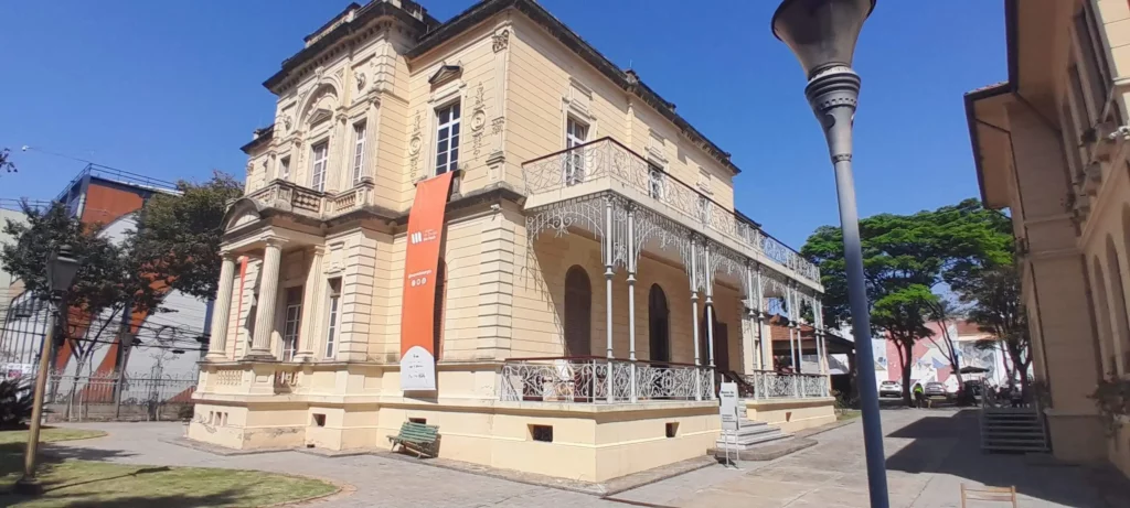 Imagem do Museu da Energia de São Paulo mostra um prédio histórico amarelo com grades de ferro ornamentadas e janelas em arco