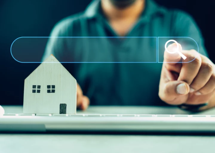 Imagem que retrata a busca de informações sobre imóveis, mostrando um modelo de casa e uma pessoa interagindo com um computador.