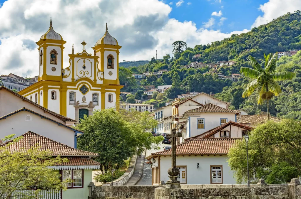 Imagem da paisagem urbana da cidade de Ouro Preto mostra igreja, construções coloniais e montanha ao fundo para ilustrar matéria sobre as cidades históricas em Minas Gerais