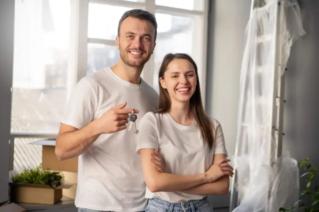 Imagem de uma casal jovem de homem e mulher sorridentes enquanto seguram a chave de uma casa nova para ilustrar matéria sobre por que morar em Votorantim
