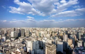 Imagem panorâmica de edifícios residenciais fotografados durante uma manhã de céu azul para ilustrar matéria sobre cidades mais verticalizadas do Brasil